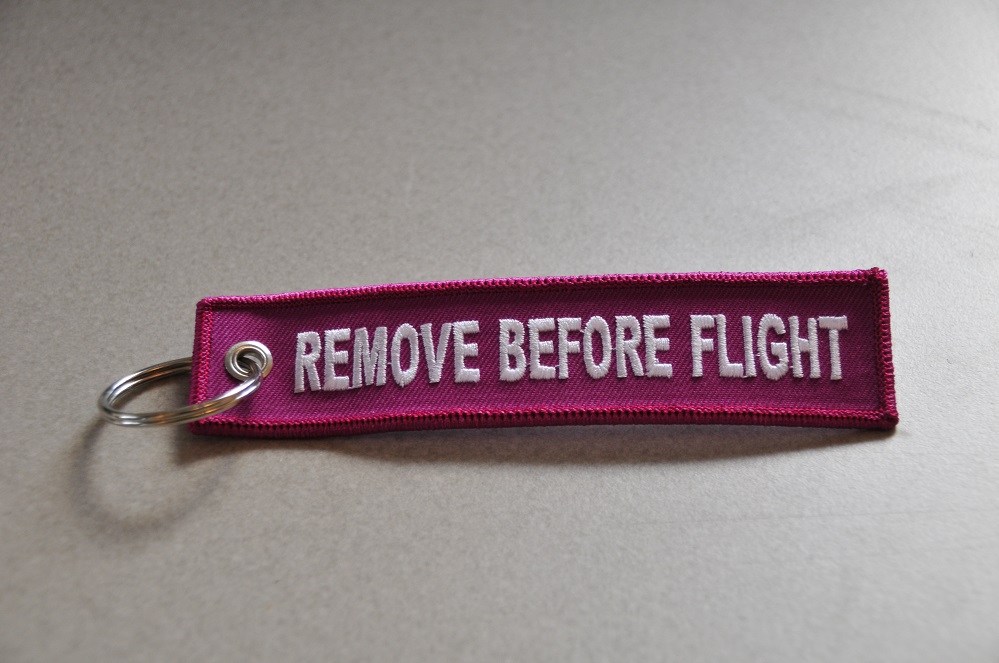 REMOVE BEFORE FLIGHT keychain keyring (pink + white letters)